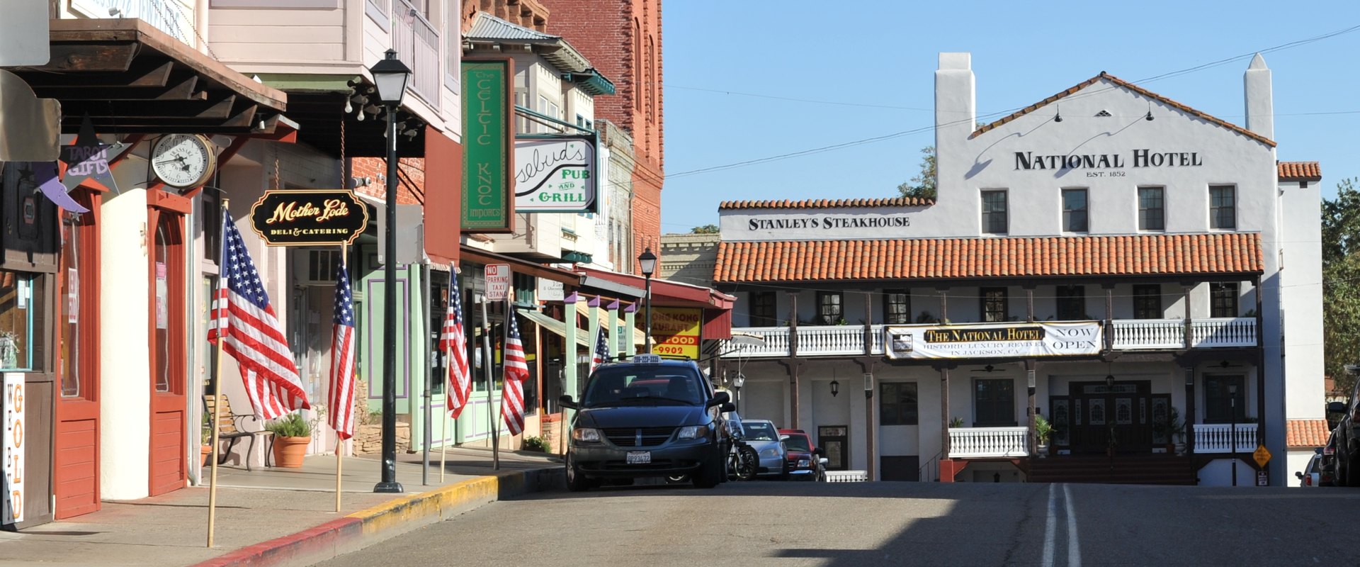 Main Street in Jackson, California: the National Hotel and Stanley's Steakhouse stand on the right, with shopfronts, a deli and a pub along the left.